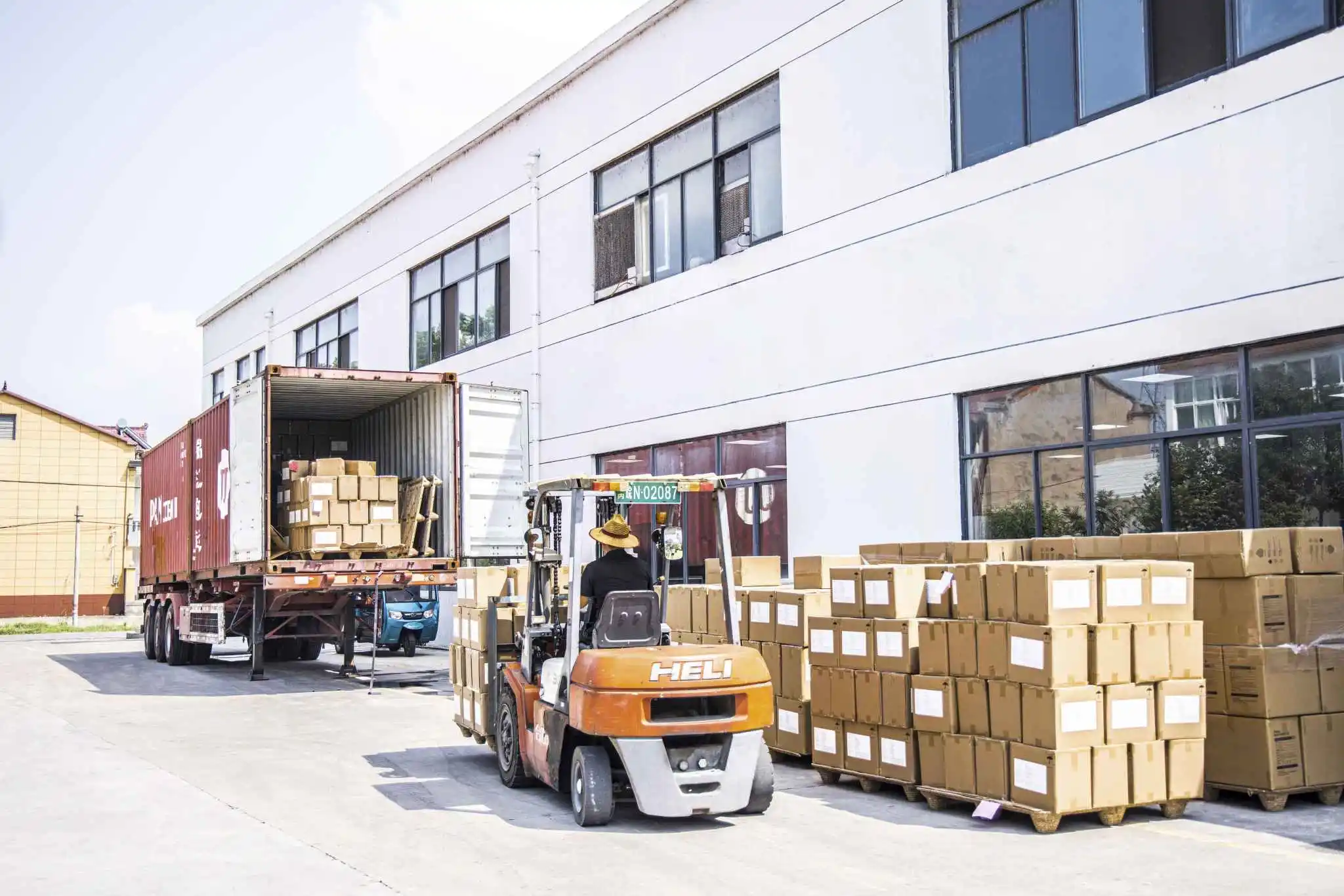 A forklift loading cardboard boxes onto a shipping container outside a warehouse for packing and delivery A forklift loading cardboard boxes onto a shipping container outside a warehouse for packing and delivery