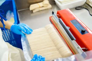 Bamboo cutlery being carefully packaged by a worker in the factory