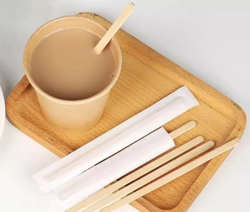 Tazza di carta con accanto dei mescolatori di legno per il caffè Tazza di carta con accanto dei mescolatori di legno per il caffè