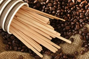 Coffee stirrers spilling from cup onto coffee beans