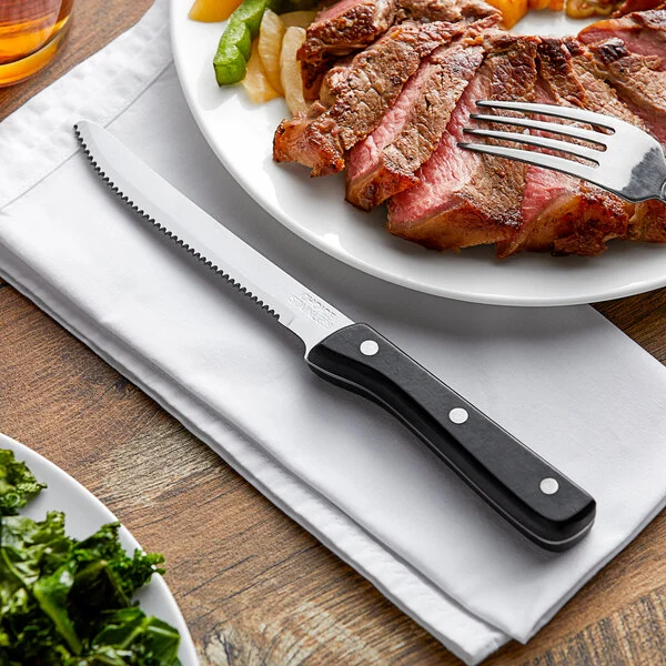 Steak knife on napkin beside sliced grilled meat Steak knife on napkin beside sliced grilled meat