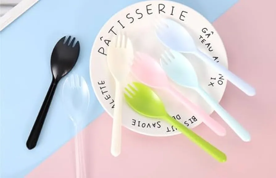 Bunte Plastik-Göffel auf weißem Dessertteller