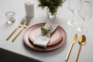 Romantic rose gold plates and gold cutlery with candles