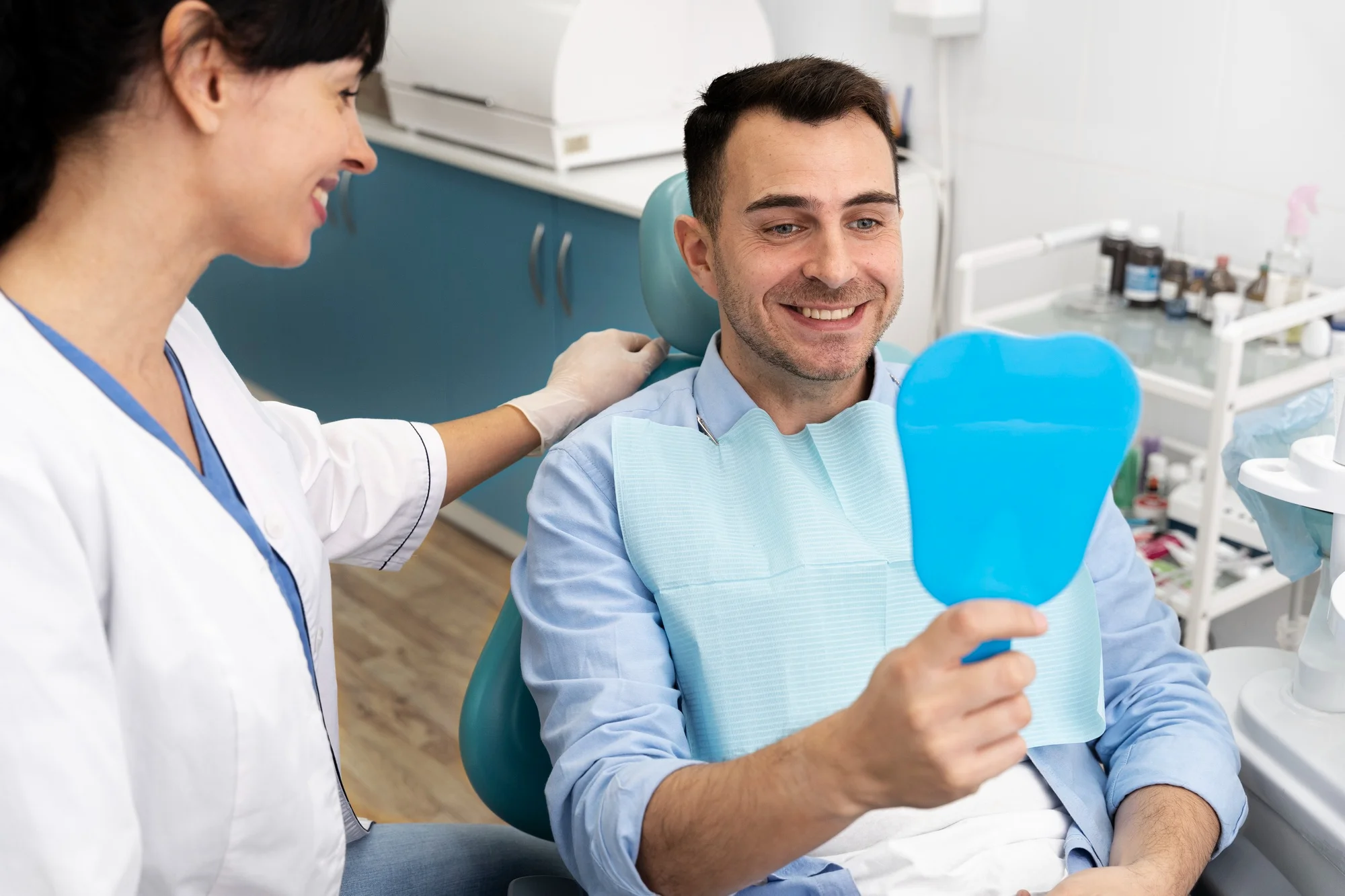 Man smiling in dentist chair with mirror Man smiling in dentist chair with mirror