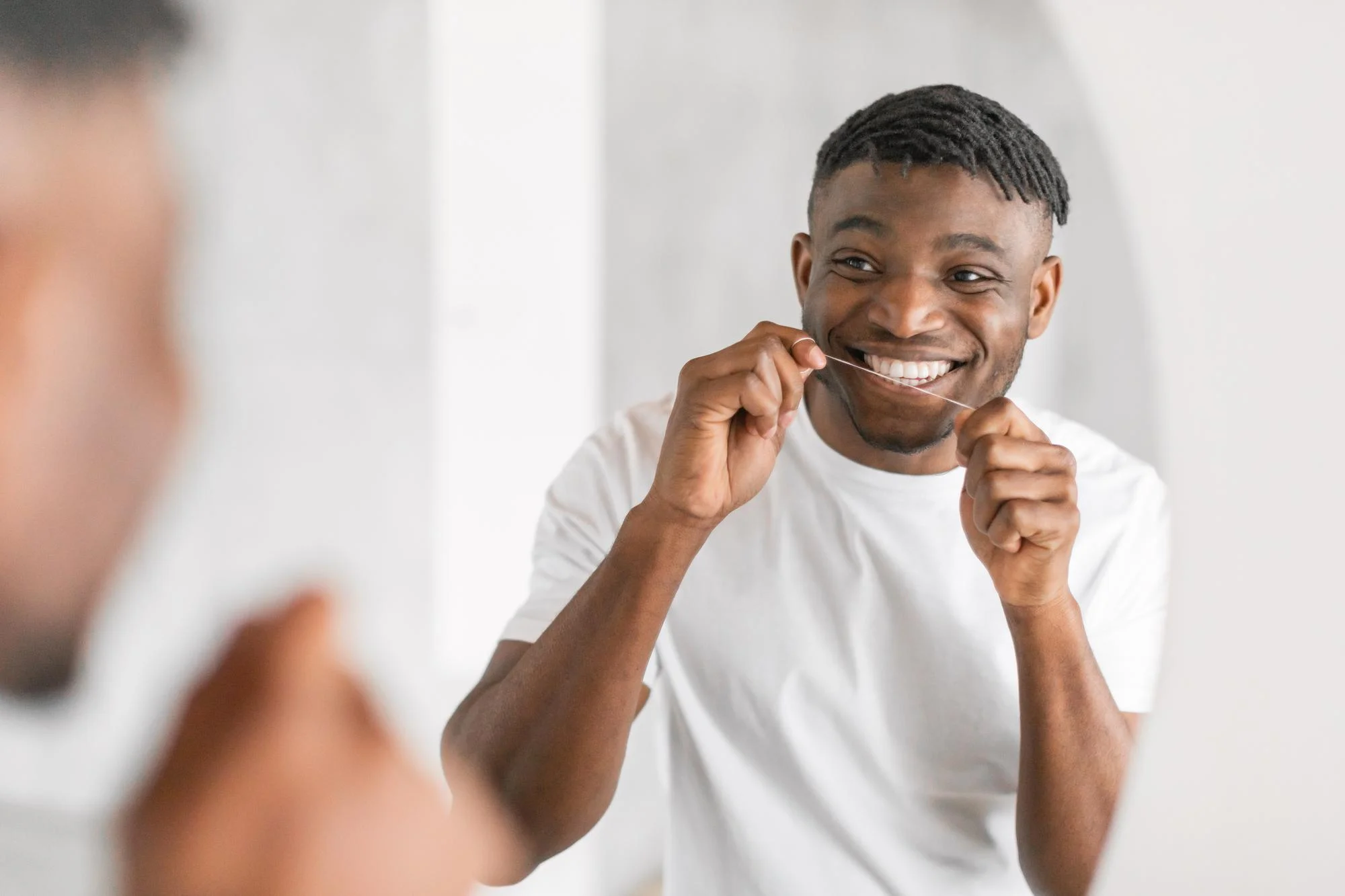 Man smiling while flossing his teeth Man smiling while flossing his teeth