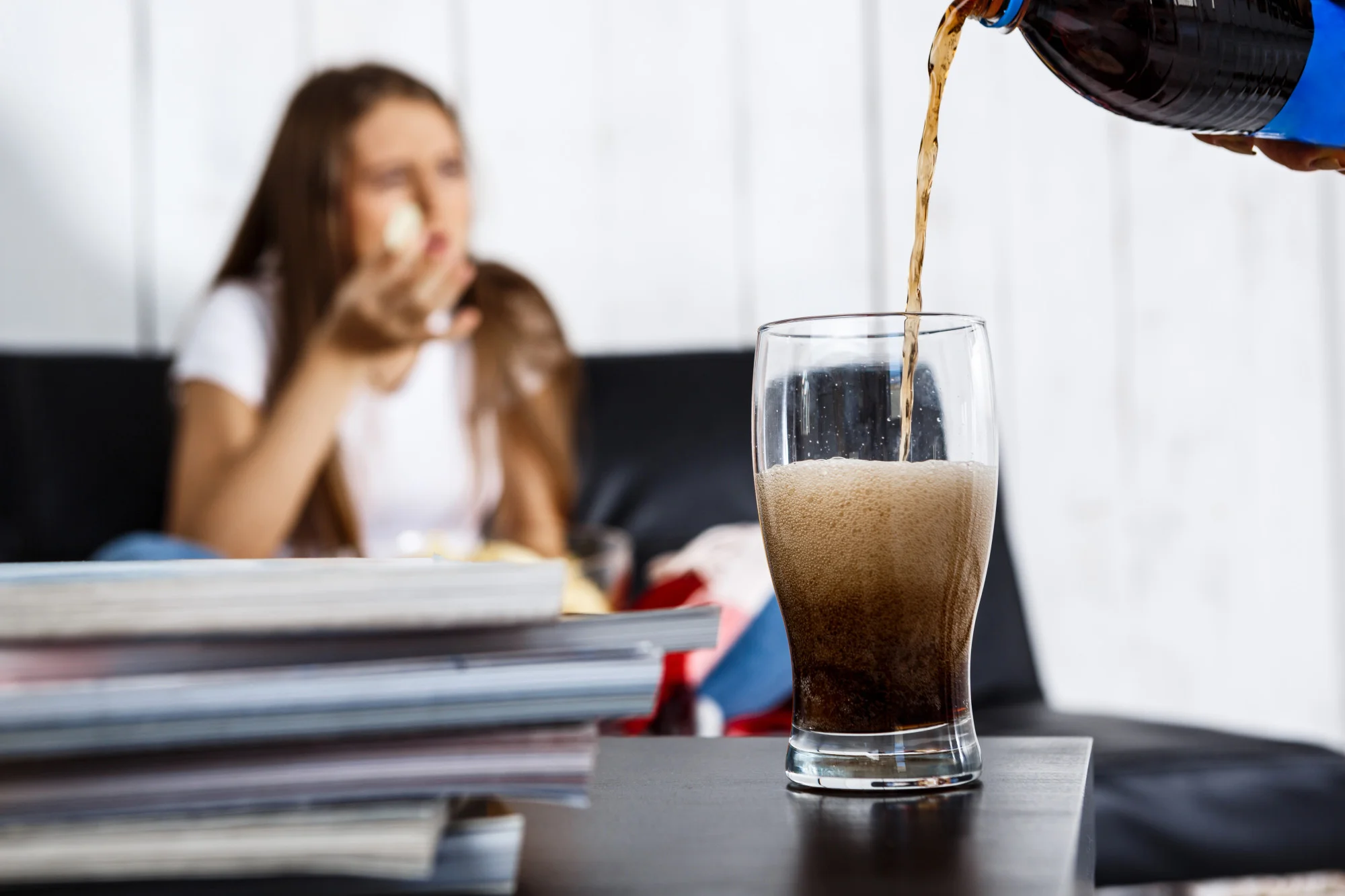 Pouring soda into glass with girl in background Pouring soda into glass with girl in background