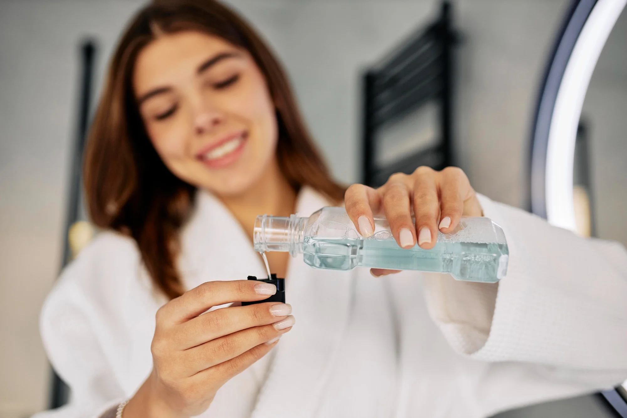 Woman pouring blue mouthwash in bathroom Woman pouring blue mouthwash in bathroom